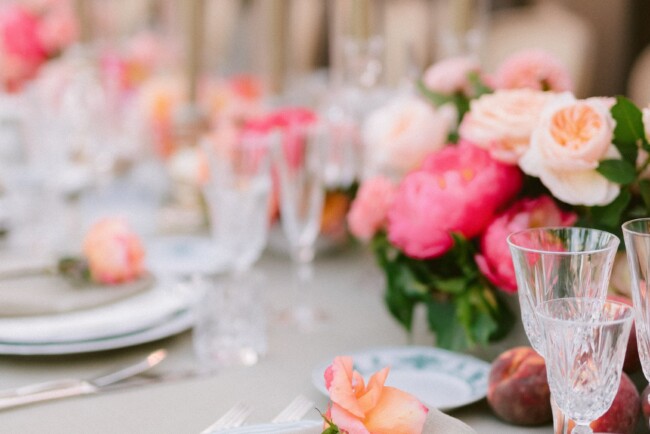 Table setting with sage color tableclothes and orange and pink flowers