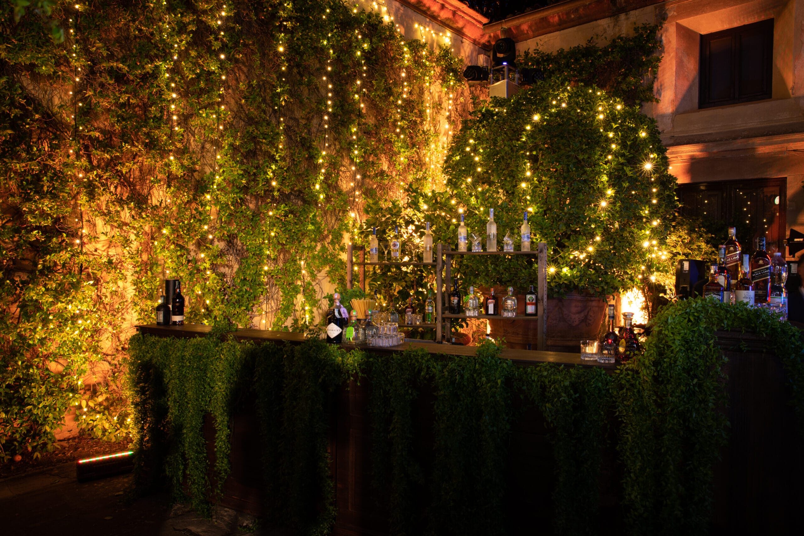 Bar station with greenery and fairlights for a secret garden style wedding in Italy