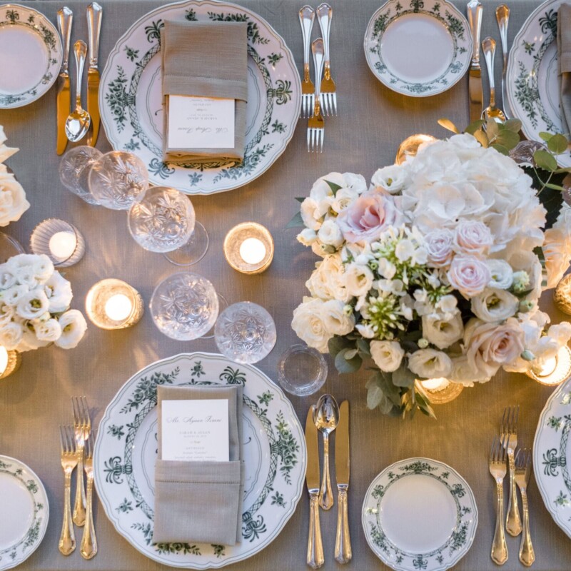 Table setting with ivory and pale rose flowers and green decorated plates